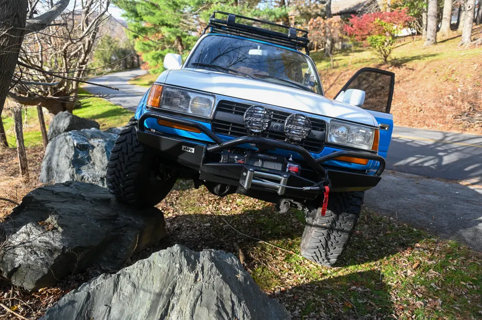 Land Cruiser with front wheel climbing rocks